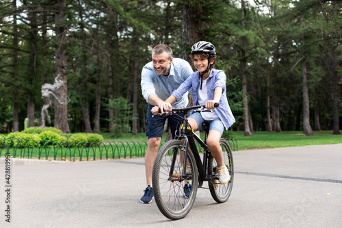 Boy learning how to ride bicycle with his happy dad