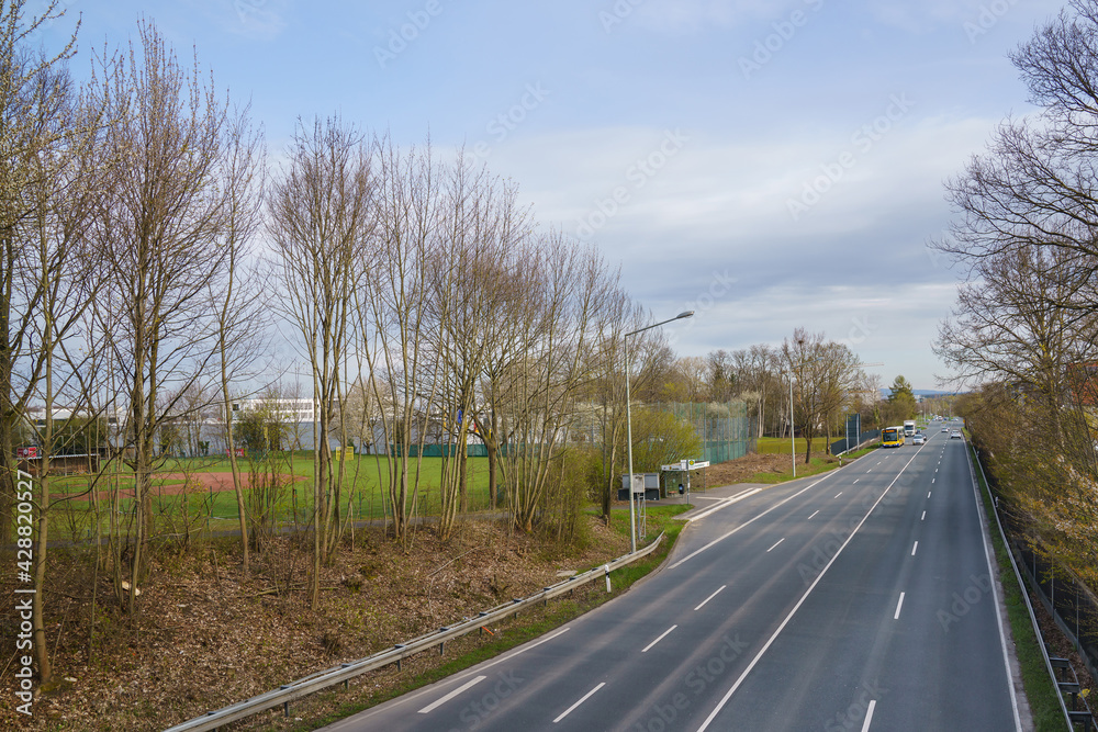 View from the bridge to the road. Bus and cars are driving along the road. View from the bridge to the road. Bus and cars are driving along the road.