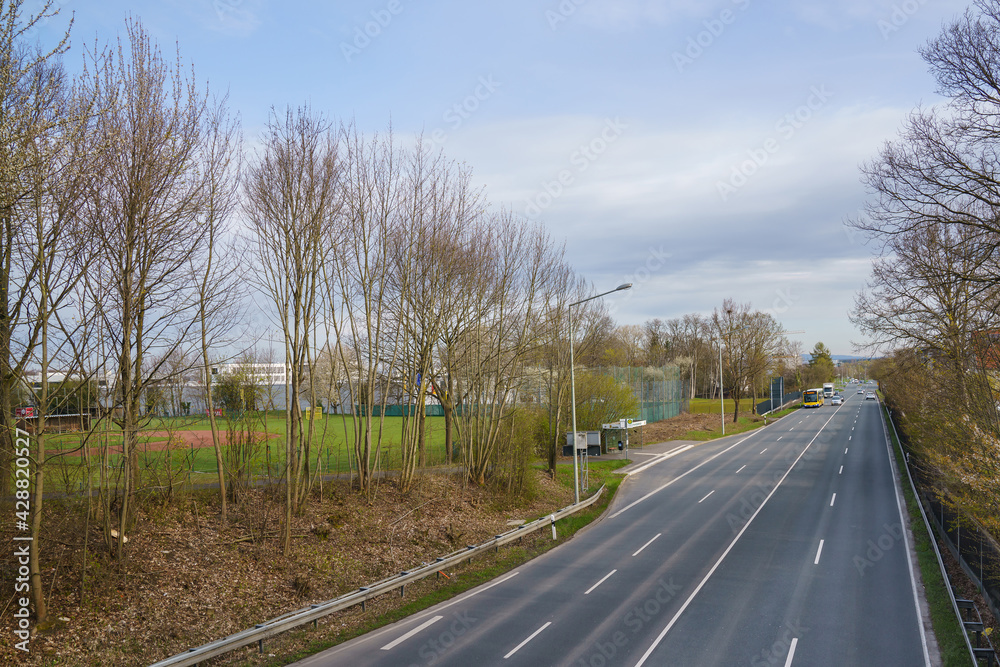 View from the bridge to the road. Bus and cars are driving along the road.