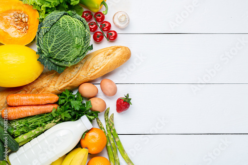 Vegetables, fruits assortment and bottle of milk on white wooden background. Vegetarian healthy food concept. Food and grocery shopping