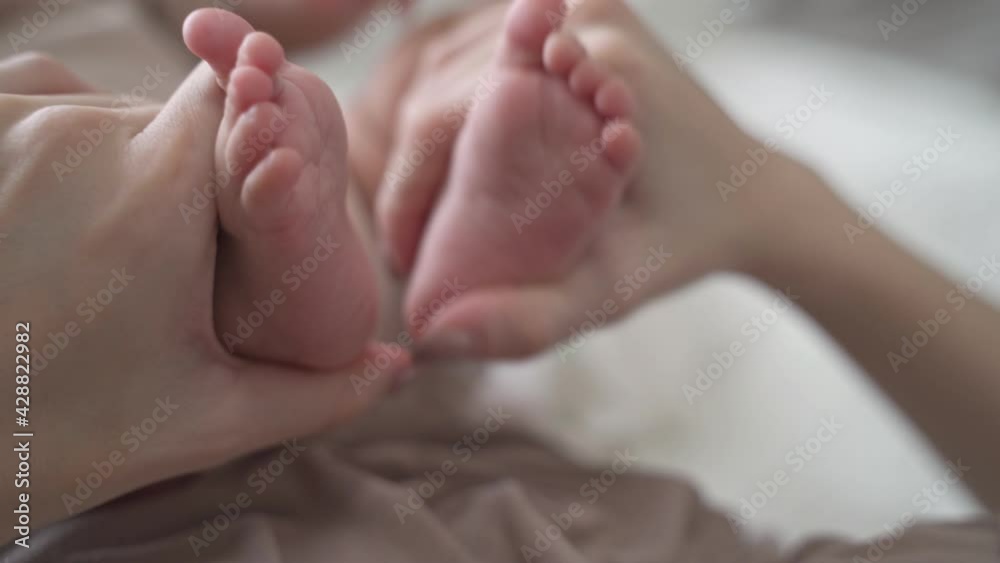 asian woman mother parent touching baby infant feet with love and care on soft bed. close up female hand holding baby foot. love protection concept. asian woman mother parent touching baby infant feet with love and care on soft bed. close up female hand holding baby foot. love protection concept.