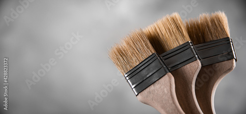 Clean fresh new paint brushes for painting on gray blurred concrete background. Close up with copy empty space for text. Banner for advertising.