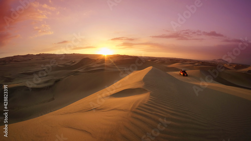 Dune buggy at the desert at sunset hour. Huacachina, Ica, Peru. Extreme sports, adventure and travel concept. Wide angle shot.