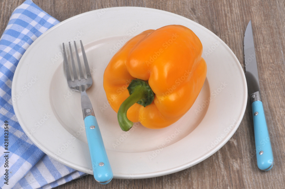 Poivron jaune dans une assiette avec des couverts en gros plan Poivron jaune dans une assiette avec des couverts en gros plan