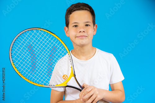 Young boy with tennis racket isolated over blue background. © Danko