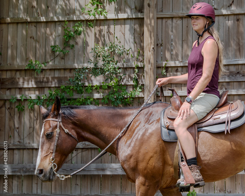 Young Woman Wearing Riding Helmet on Brown Horse Looking into the Distance