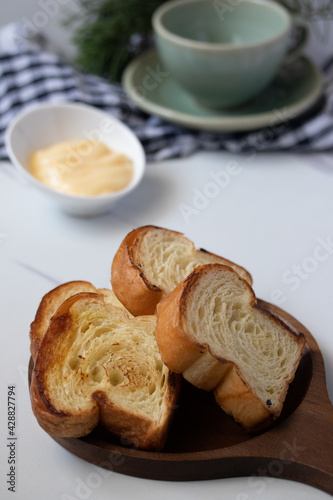 Toast in wooden plate with cheese on gray background