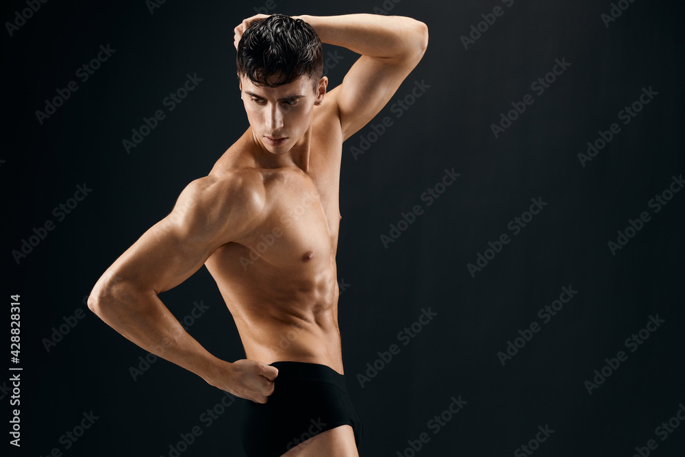 Naklejka premium man with a pumped-up torso athlete dark background studio