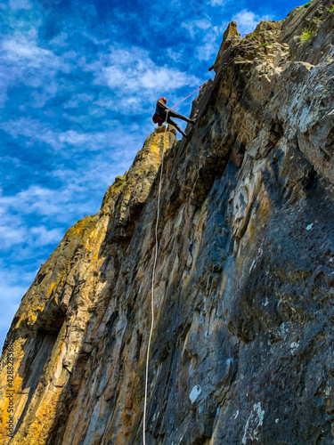 rock climber on the top of mountain, down the mountain with a rope, abseiling
