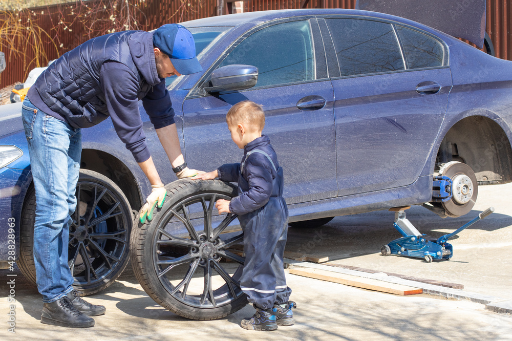 Father and son are fixing the car. The son helps the dad. Happy Father's Day. Father and son are fixing the car. The son helps the dad. Happy Father's Day.