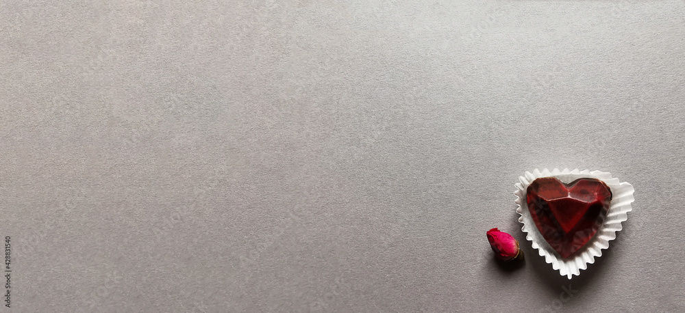 On a gray background useful candy heart and a small rosebud On a gray background useful candy heart and a small rosebud