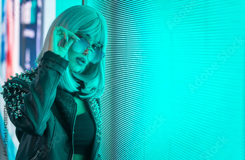 Photography Image of a beautiful young woman posing against a led panel.