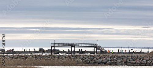 panoramic view to the seaside breakwater with the people angling for the spring spawning fish