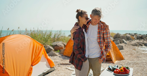 Happy couple embracing each other during camping weekend, family hobbies