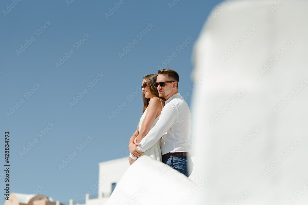 Happy couple hugging and laughing together with a view of Santorini