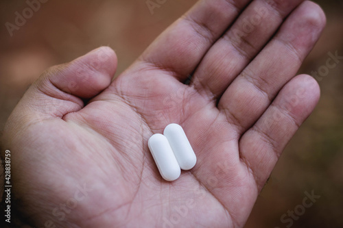 In this photo illustration two medicine pills in a man's hand. Ivermectin and Chloroquine not used in the treatment of Covid-19.