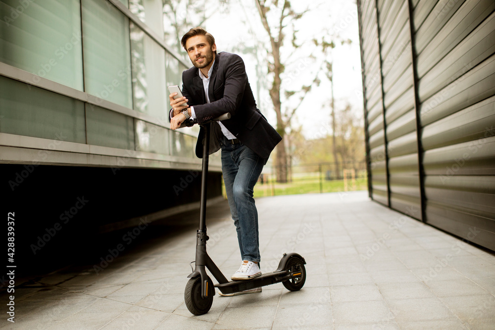 Young businessman using mobile phone on electric scooter Young businessman using mobile phone on electric scooter