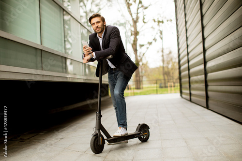 Young businessman using mobile phone  on electric scooter