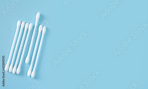 Flay lay of white plastic cotton sticks or swabs top view on blue background