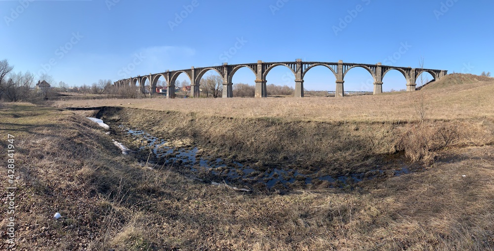 Panorama of the old abandoned Mokrinsky railway bridge in the spring next to the stream 
