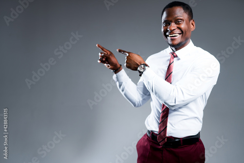 Happy african american businessman in shirt and tie points fingers to the side smiling. Place for inscriptions photo