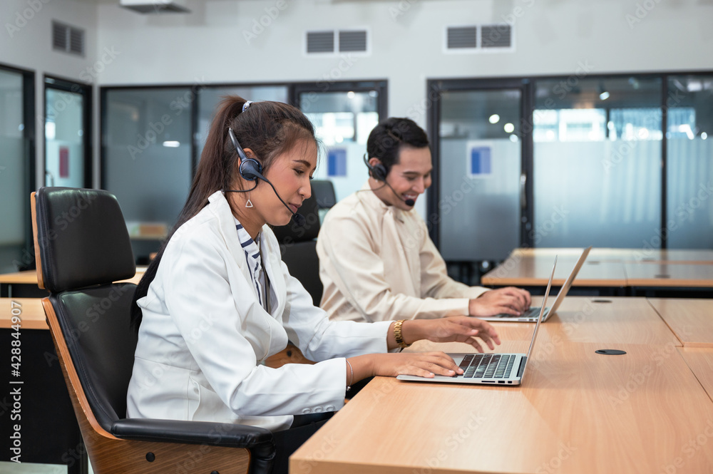 Operator asian woman agent with headset working with laptop on customer consultation in the office with colleague at workplace Operator asian woman agent with headset working with laptop on customer consultation in the office with colleague at workplace