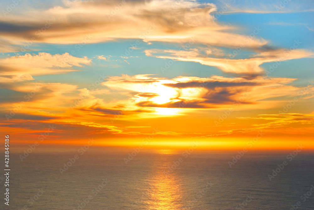 orange sunset above sea with clouds covering the sun
