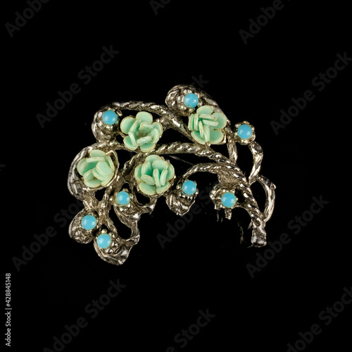 Round antique brooch with precious stones and crystals in the shape of a flower. Vintage brooch in the shape of a flower