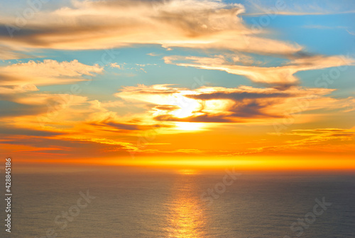 orange sunset above sea with clouds covering the sun
