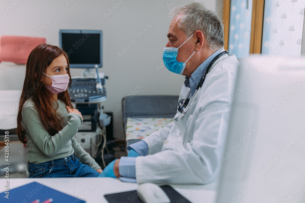 Obraz premium Doctor with face mask controlling the health of little girl
