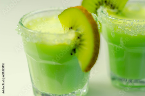 Fruit shot drink based on alcohol, liqueur and cream, decorated with green sugar crystals and a slice of fresh kiwi