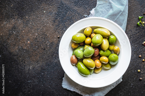pitted olives in a plate on the table different varieties of fruits  vegan or vegetarian food keto or paleo diet snack trend meal copy space food background rustic. top view 