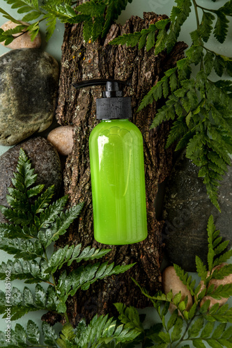 Bottle with dispenser on natural background. Cosmetic container mockup with place for text. Natural skincare beauty product concept.