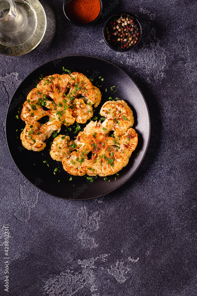 Cauliflower steak with spices cooked in the oven, top view. Cauliflower steak with spices cooked in the oven, top view.