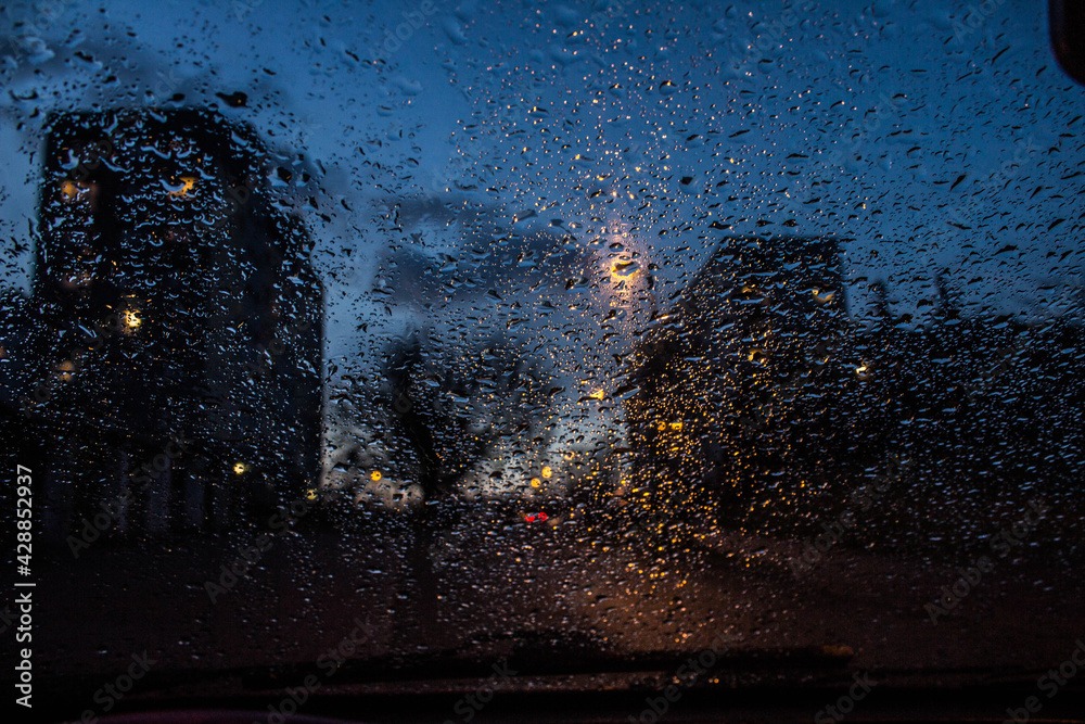 Fototapeta premium View from the car window through the rain in the evening. Background.