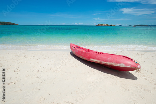 Red Kayak at the tropical beach at beautiful Clear day. Beautiful clear sand beach and tropical light blue sea. Soft wave blue ocean on sandy beach. Sallow water, Clear water. Seaside. Copy space. © setthawuth