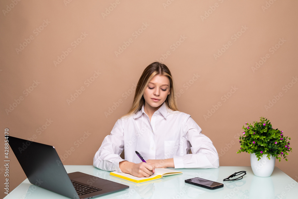 Young pretty business woman sitting at table and taking notes in notebook. Young pretty business woman sitting at table and taking notes in notebook.