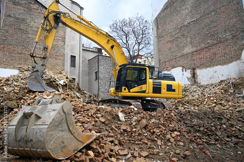 Earth moving machine tearing down an old building