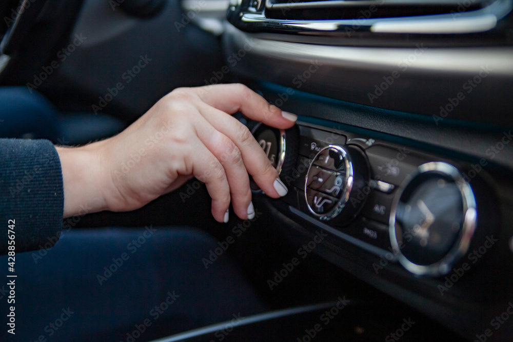 a woman's hand turns the knob for adjusting the climate control system in a modern premium car. setting a comfortable temperature in the car. comfortable travel by car