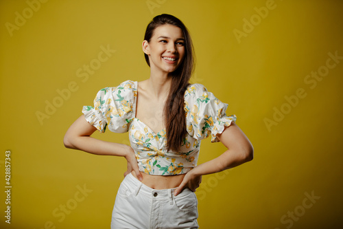 Smiling beautiful girl is posing on yellow background.