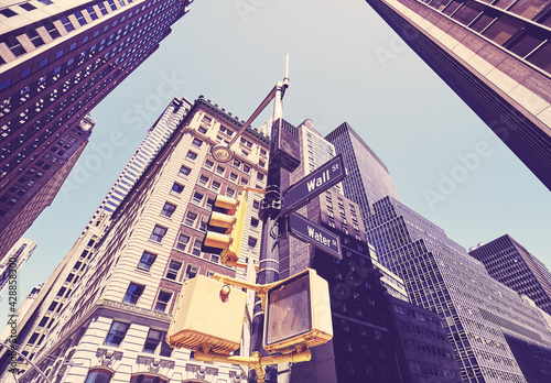 Looking up at Wall Street and Water Street signs, color toning applied, New York City, USA.