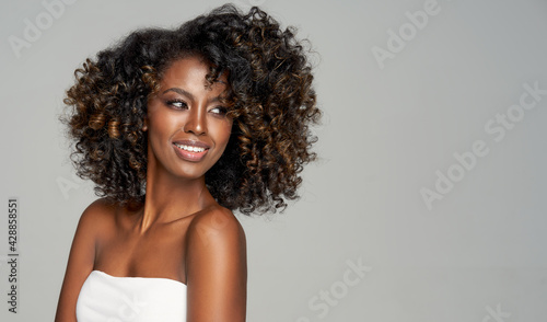 Portrait of happy black woman isolated on gray looking right on empty space