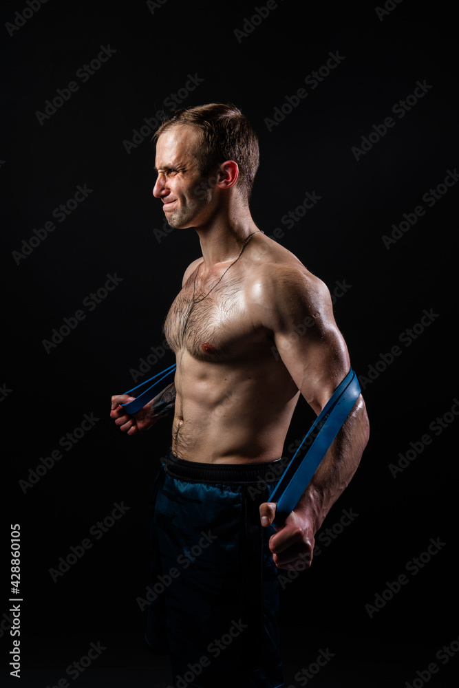 Man on black background keeps dumbbells pumped up in fitness active chest black, athlete muscular workout athletic healthy pectoral. handsome adult, gym fit With a ribbon in hand, the fitness gum is