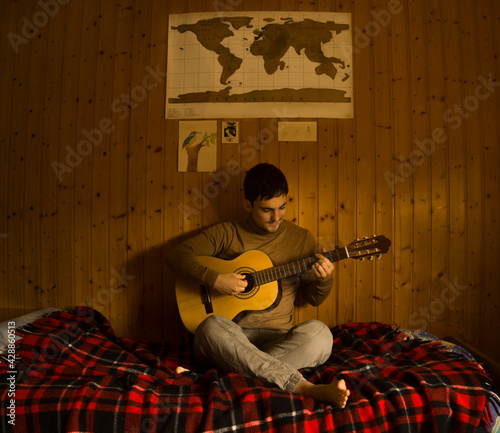 Enjoying carefree at home. Happy young man playing guitar while sitting on the sofa at home.