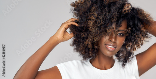 Sexy black woman playing with her afro hair isolated on gray background photo