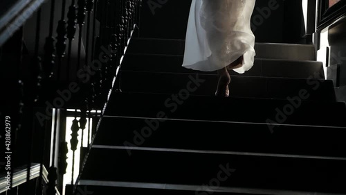 person on stairs. a girl in an evening dress climbs the stairs. close-up. the girl goes to a brighter future. A light in the end of a tunnel. 