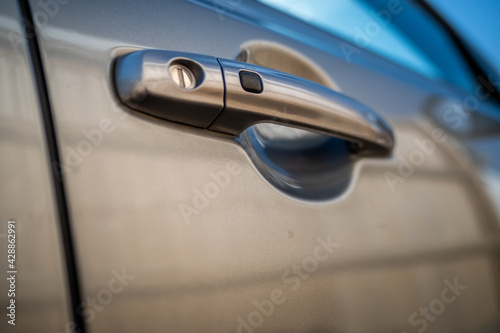 offside front door handle of a grey Suzuki motor vehicle with intentional shallow depth of field and bokeh
