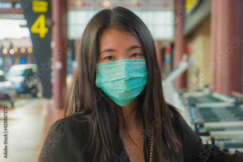 travel and holiday in times of covid-19 - young pretty Asian Chinese woman with backpack waiting at airport departure wearing protective mask against covid19 virus