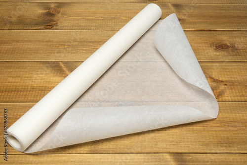 Baking paper roll on wooden table.