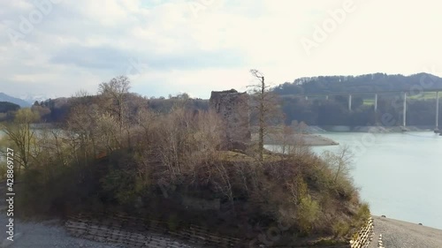 Ruins of Pont en Ogoz castle on Oiseaux island, Gruyere lake in Switzerland. Aerial circling photo